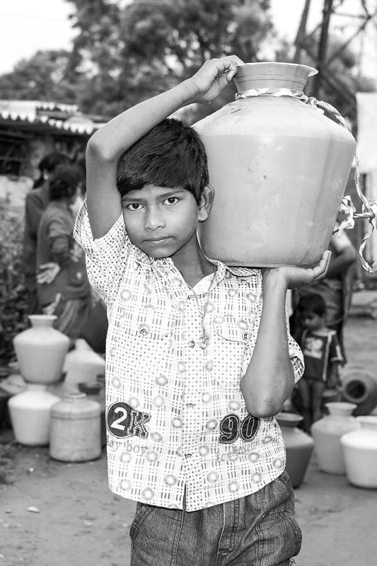 Water portraits - A young boy shouldering the responsibility of fetching water in the morning for his family from the community borewell – Bangalore city, Karnataka